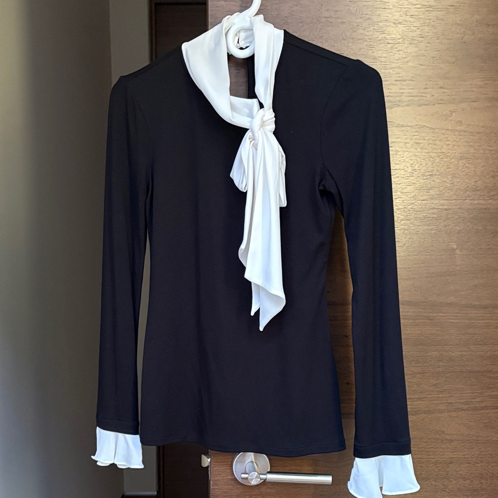 Elegant black top with cream tie and cream sleeve accents.